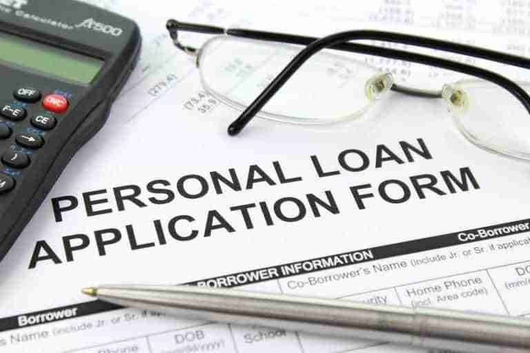 A close-up image of a bad credit personal loan application form with a calculator and eyeglasses resting on top, suggesting financial planning or the process of applying for a loan.