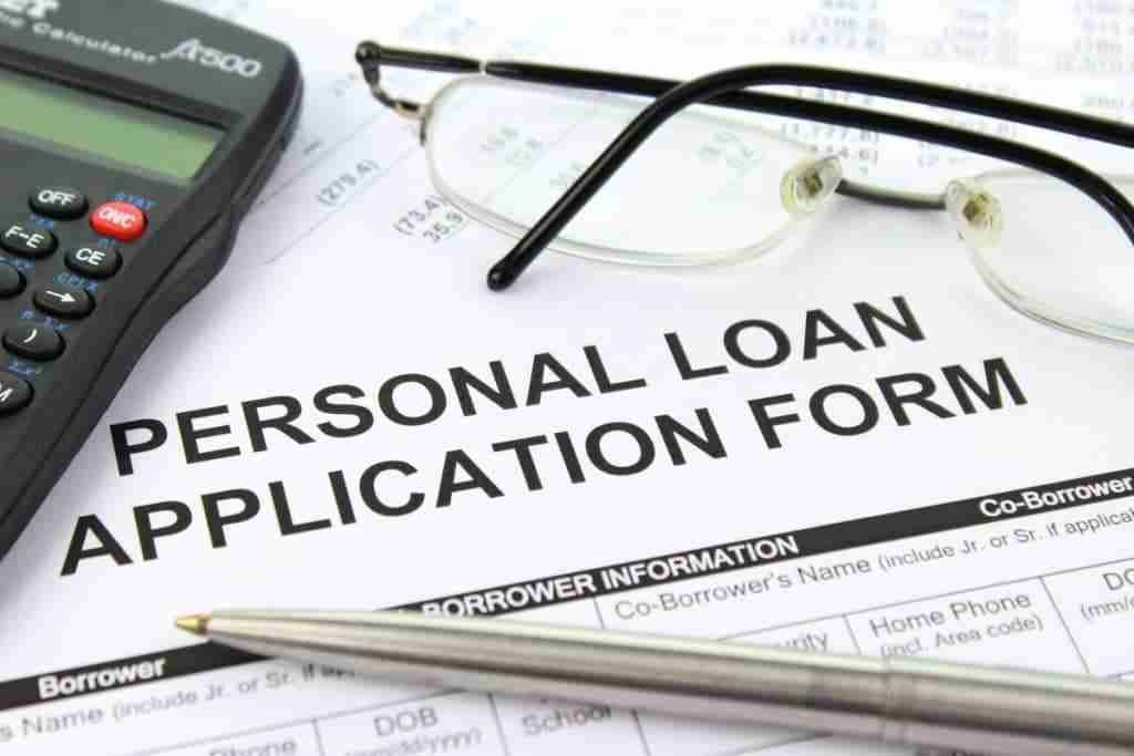 Bad Credit Personal Loan Online Approvals A close-up image of a bad credit personal loan application form with a calculator and eyeglasses resting on top, suggesting financial planning or the process of applying for a loan.
