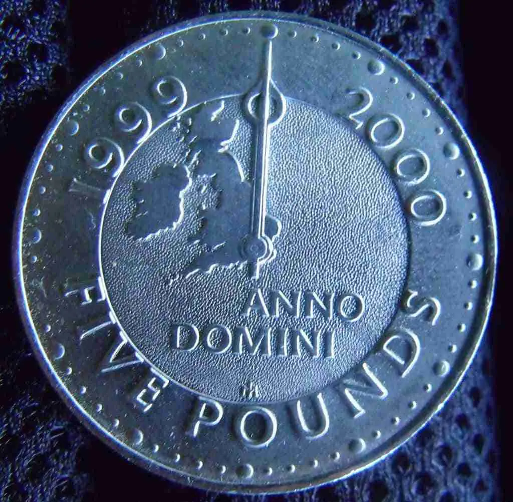 A commemorative two-pound coin marking the turn of the millennium, with the years 1999 and 2000 split by a stylized clock hand, under the inscription "Anno Domini",