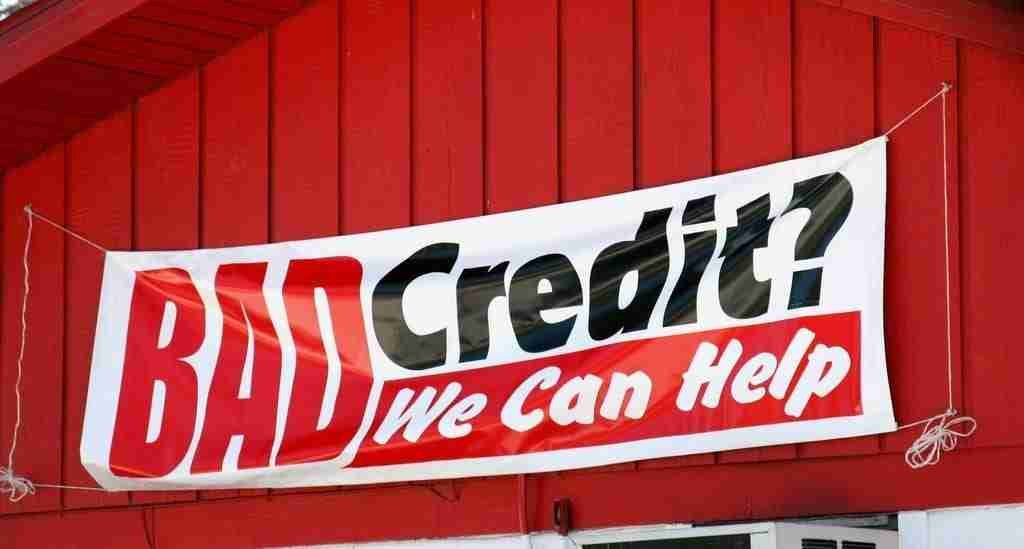 A red and white banner hanging on a red wall with the text "4000 loan bad credit? We can help," offering financial services for those with poor credit history.
