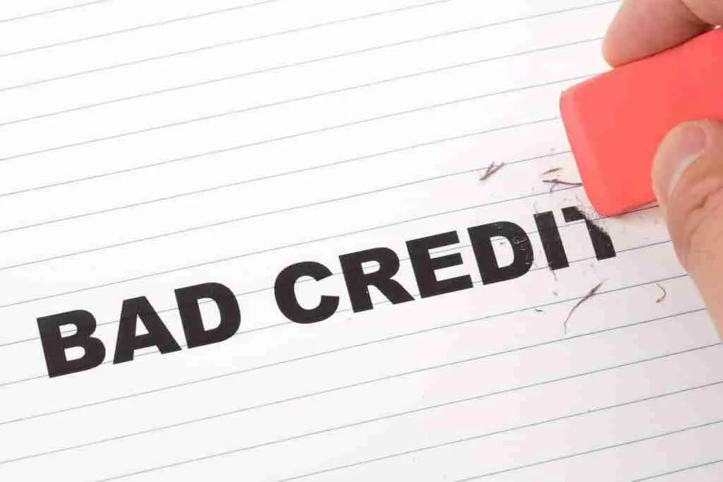 Erasing bad credit concept: a hand removing the word "bad" from "bad credit" with an eraser, symbolizing how to get a loan with bad credit or financial reputation improvement.