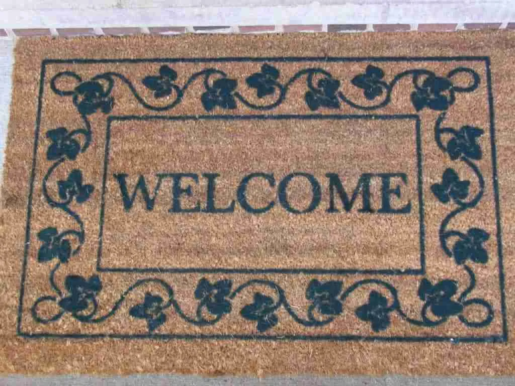 A rectangular welcome finance mat with ornate black borders and the word "welcome" in the center.