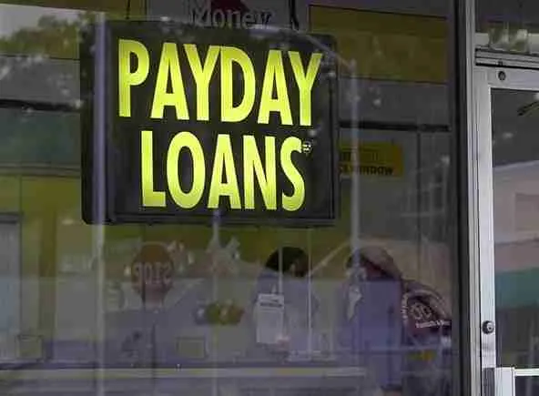 Neon sign advertising "one hour payday loans" in a storefront window indicating financial services for short-term borrowing.