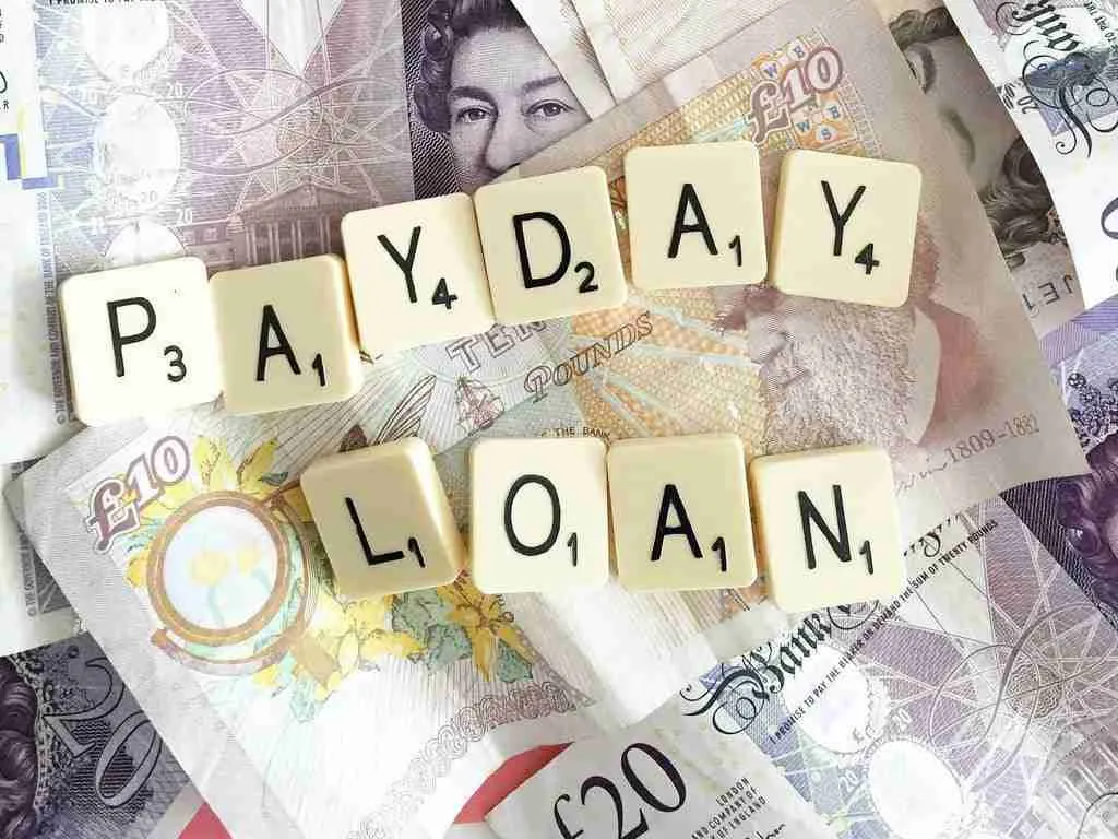 Scrabble tiles spelling out "payday loan" on a background of British capital cash.