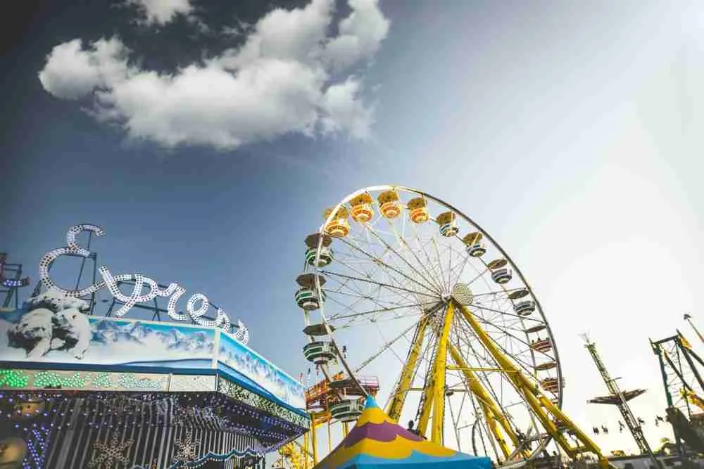 An amusement park on a sunny day, featuring a ferris wheel reaching towards the sky, with a partly cloudy backdrop, offers express loans for visitors.