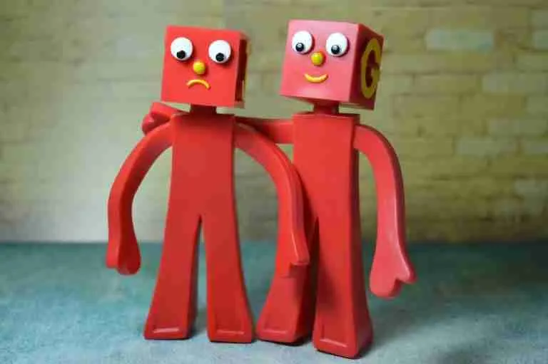 Two whimsical red plastic figures with googly eyes and alphabet letters on their heads standing side by side against a pastel background. buddy loans.